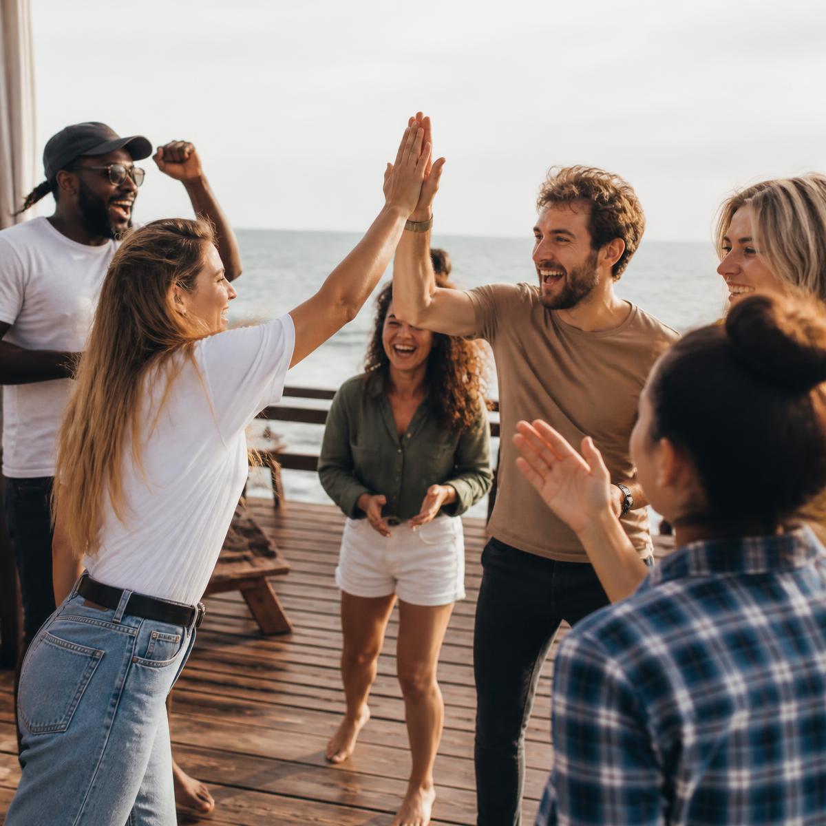 A group cheering and high-fiving on a seaside deck